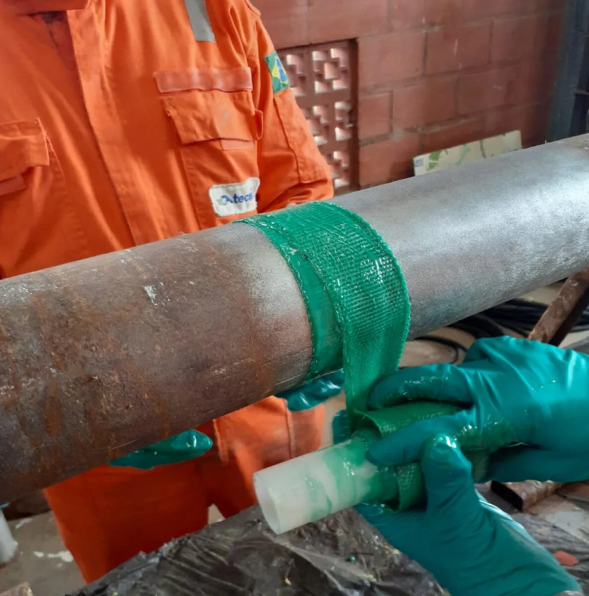 Aplicação manual de fibra saturada com resina termoendurecível sobre duto preparado